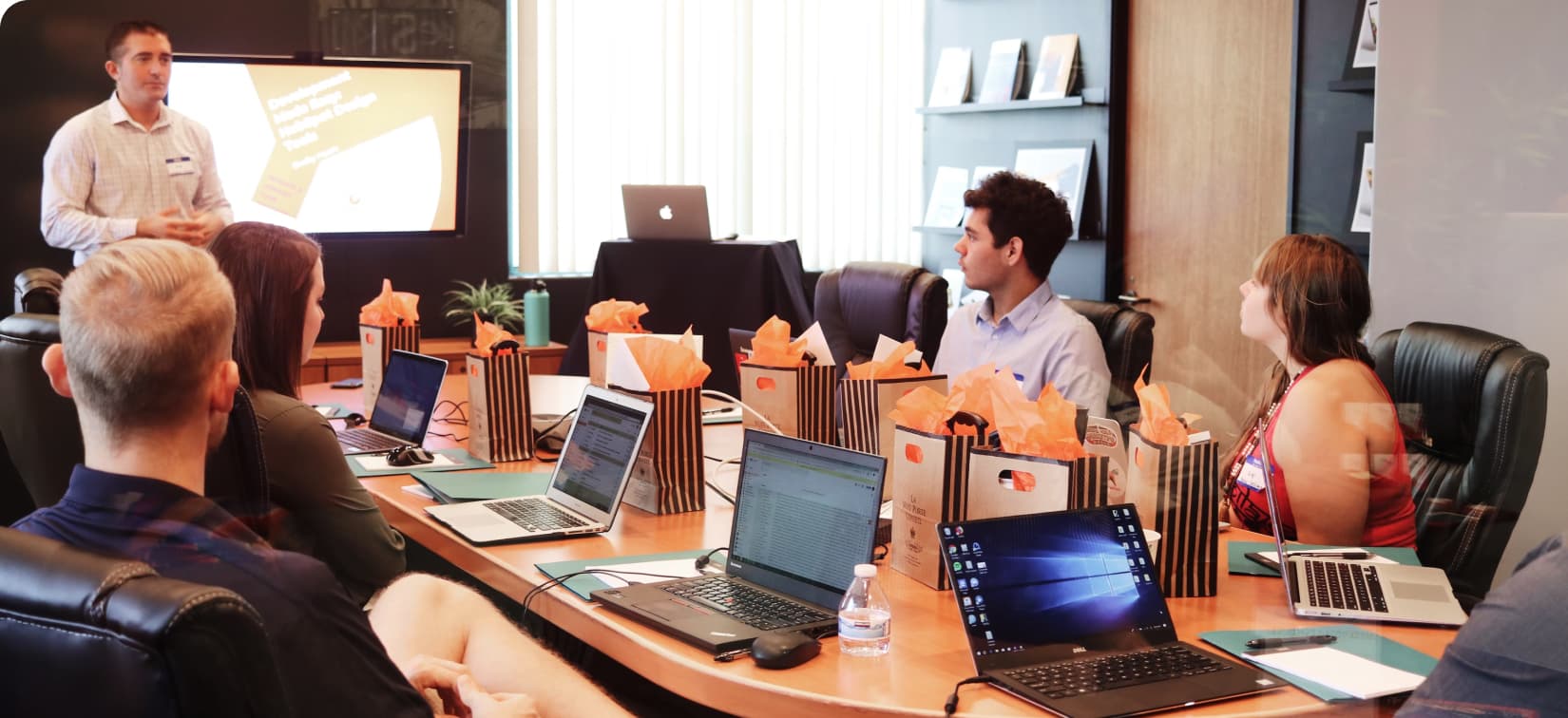 A group around a table listening to a lecturer